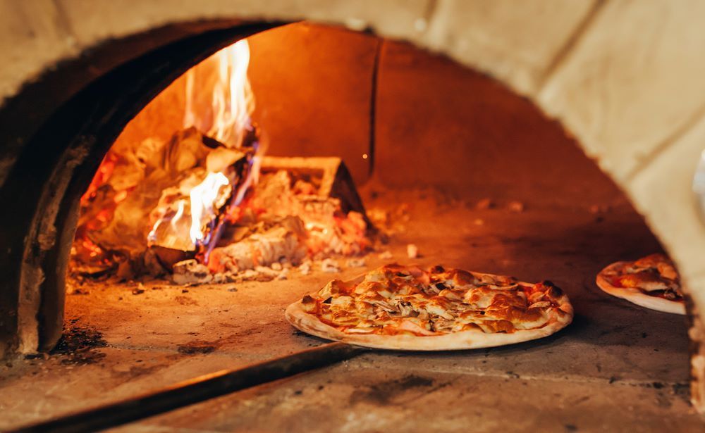 A Pizza is Being Cooked in a Wood Fired Oven — Michelangelos Pizza & Pasta in Aitkenvale, NSW