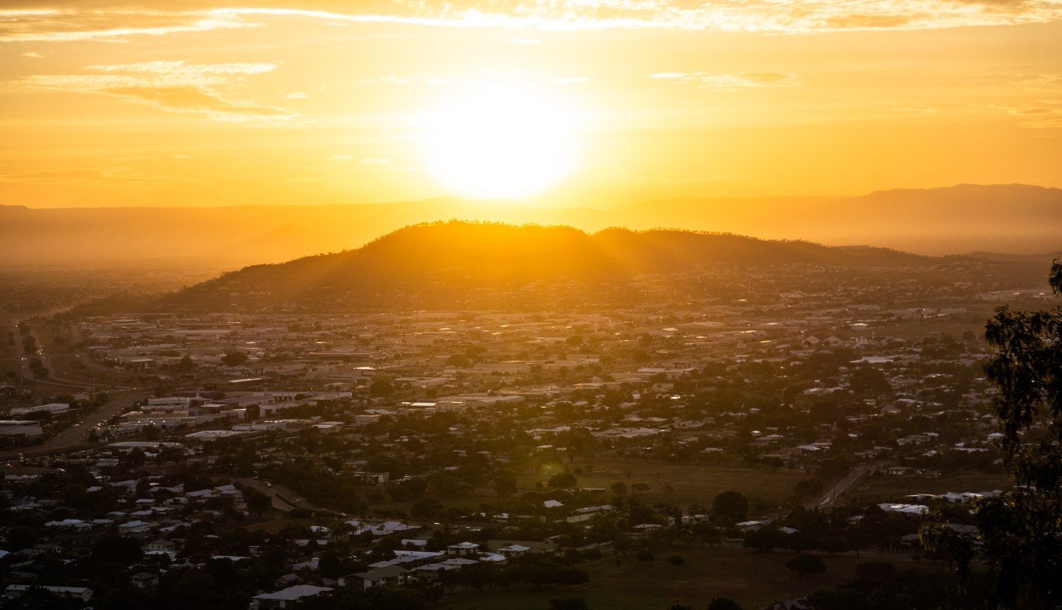 The Sun is Setting Over a City With Mountains in the Background — Michelangelos Pizza & Pasta in Mount Louisa, QLD