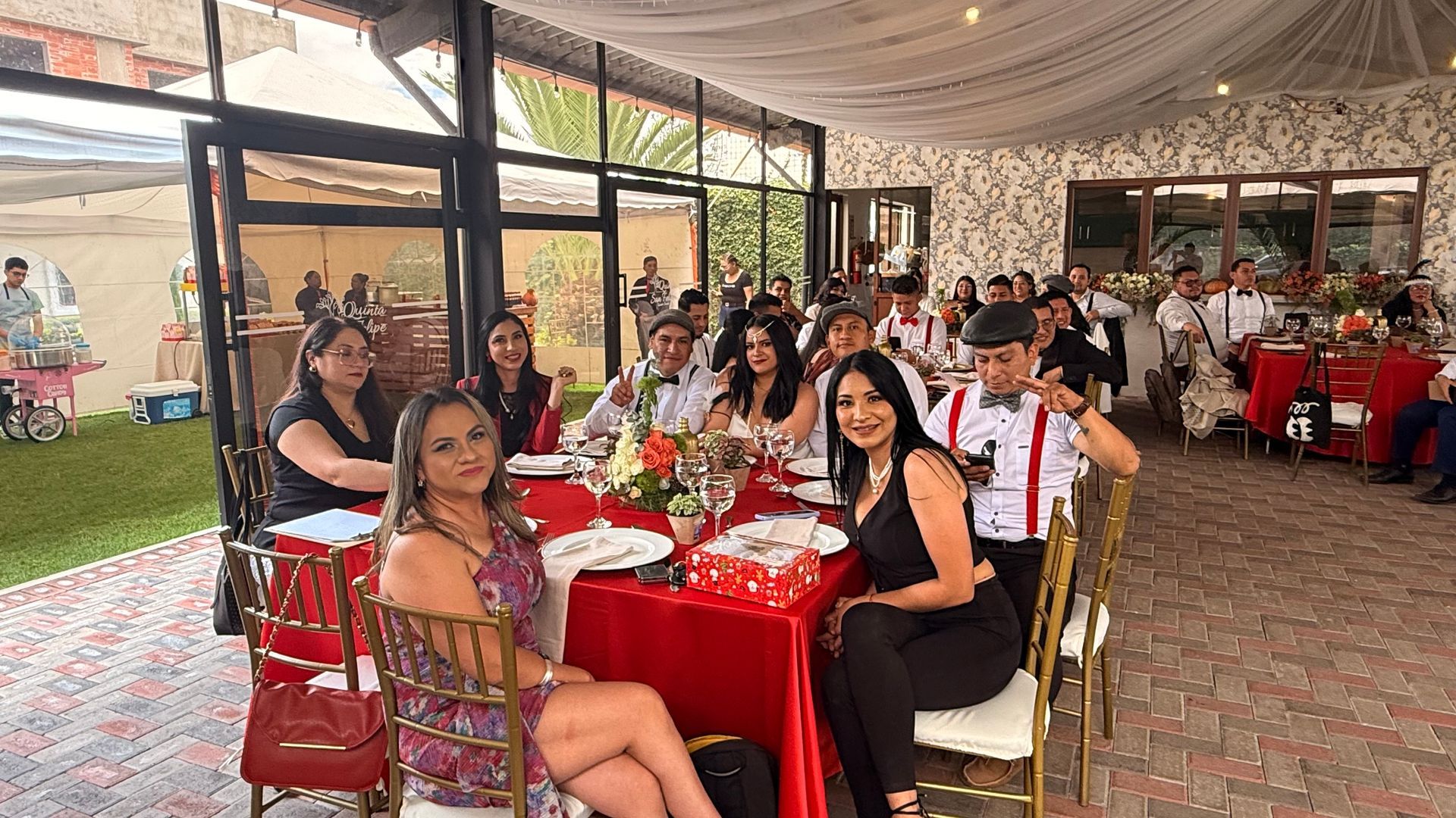 Los invitados se sentaron en mesas rojas bajo una carpa decorada en un banquete festivo al aire libre.