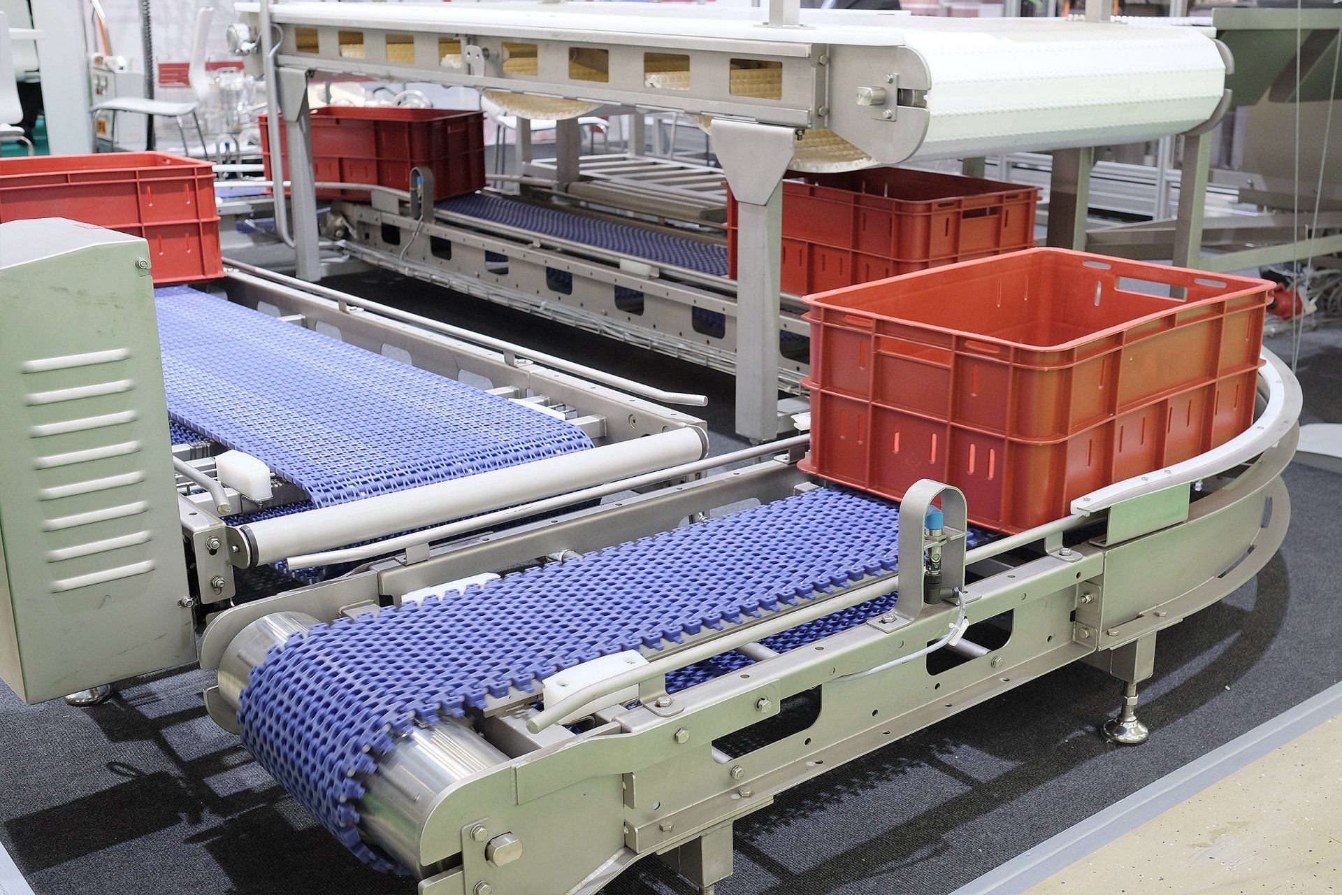 Sistema de transporte industrial que traslada paquetes de tela azul a contenedores de plástico rojo.