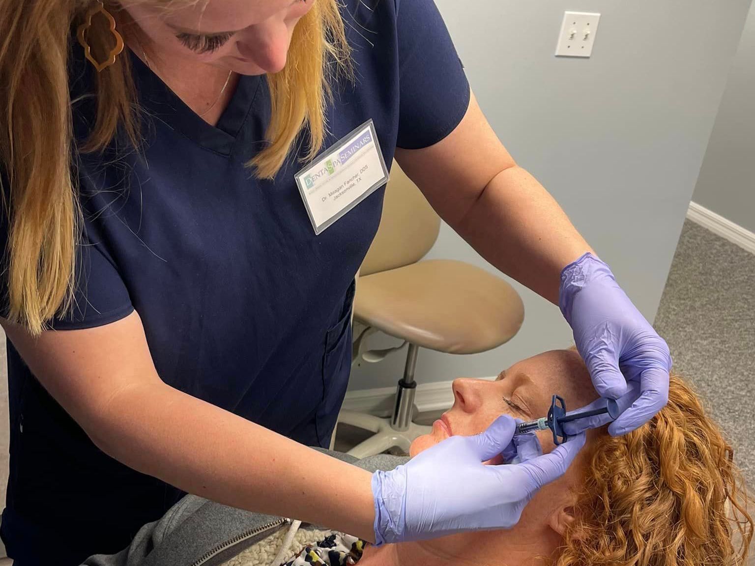 Woman receiving injection near eye from someone wearing gloves. Clinic setting.