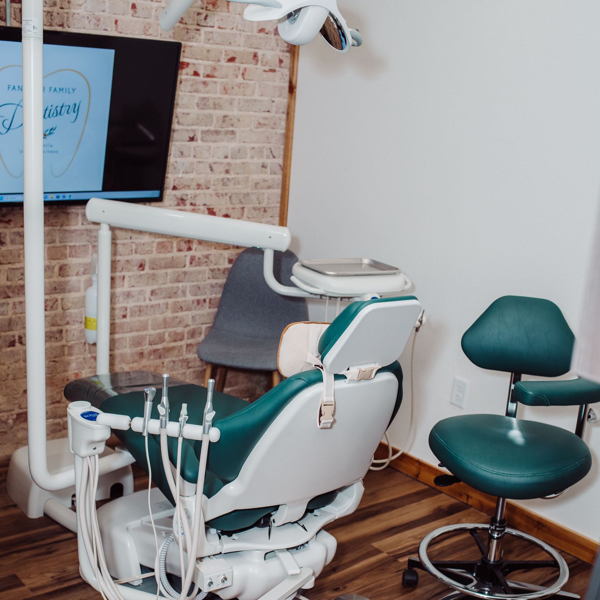 Two dental staff with a child in a dental chair; one smiles.