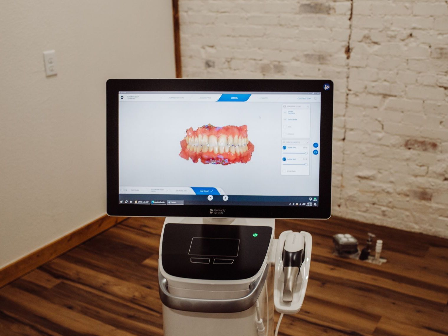 Dental scan display showing teeth model, mounted on a medical device in an office.