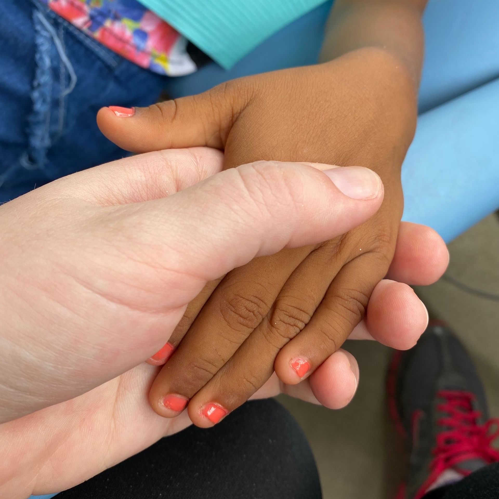 Person holding child's hand. Both hands have painted nails; the child's are coral.
