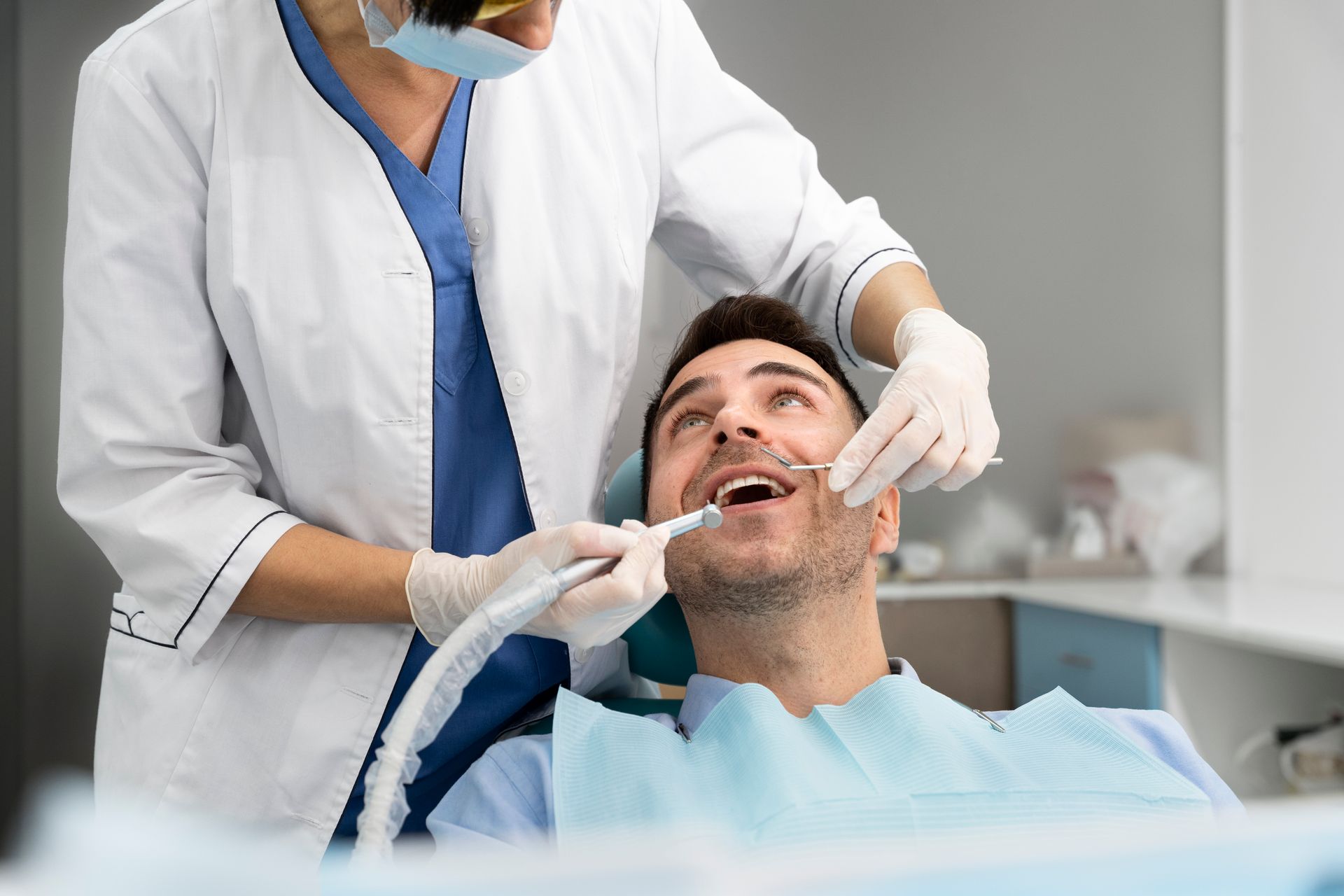 Dentist cleaning a patient's teeth in a dental office.