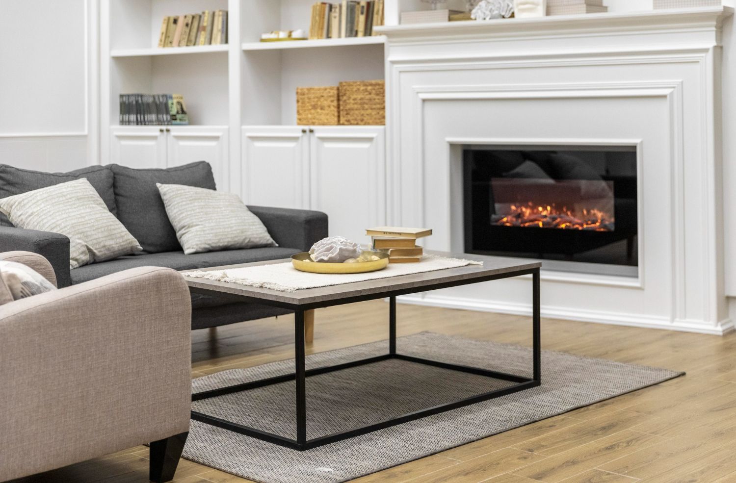 Modern living room with white fireplace, gray sofa, and coffee table on a rug