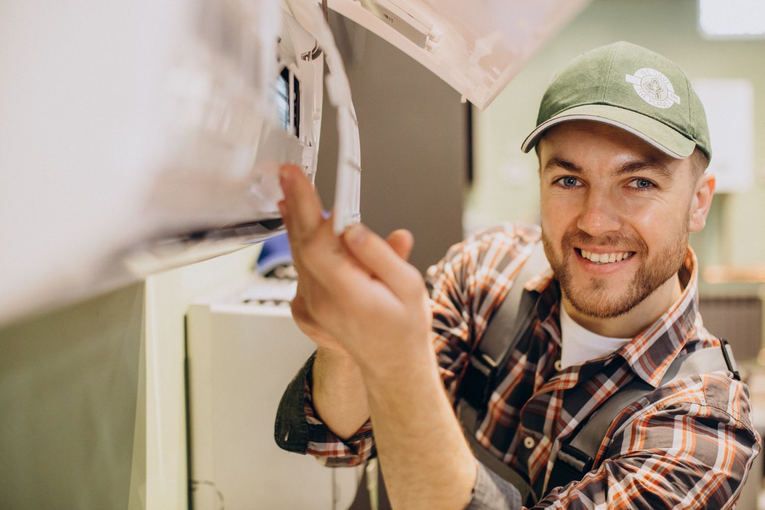 Technician installing a wall-mounted device, smiling and holding a screwdriver in a home interior