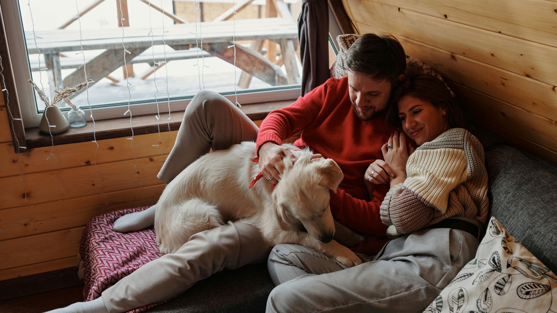 A man and a woman are sitting on a couch with a dog.