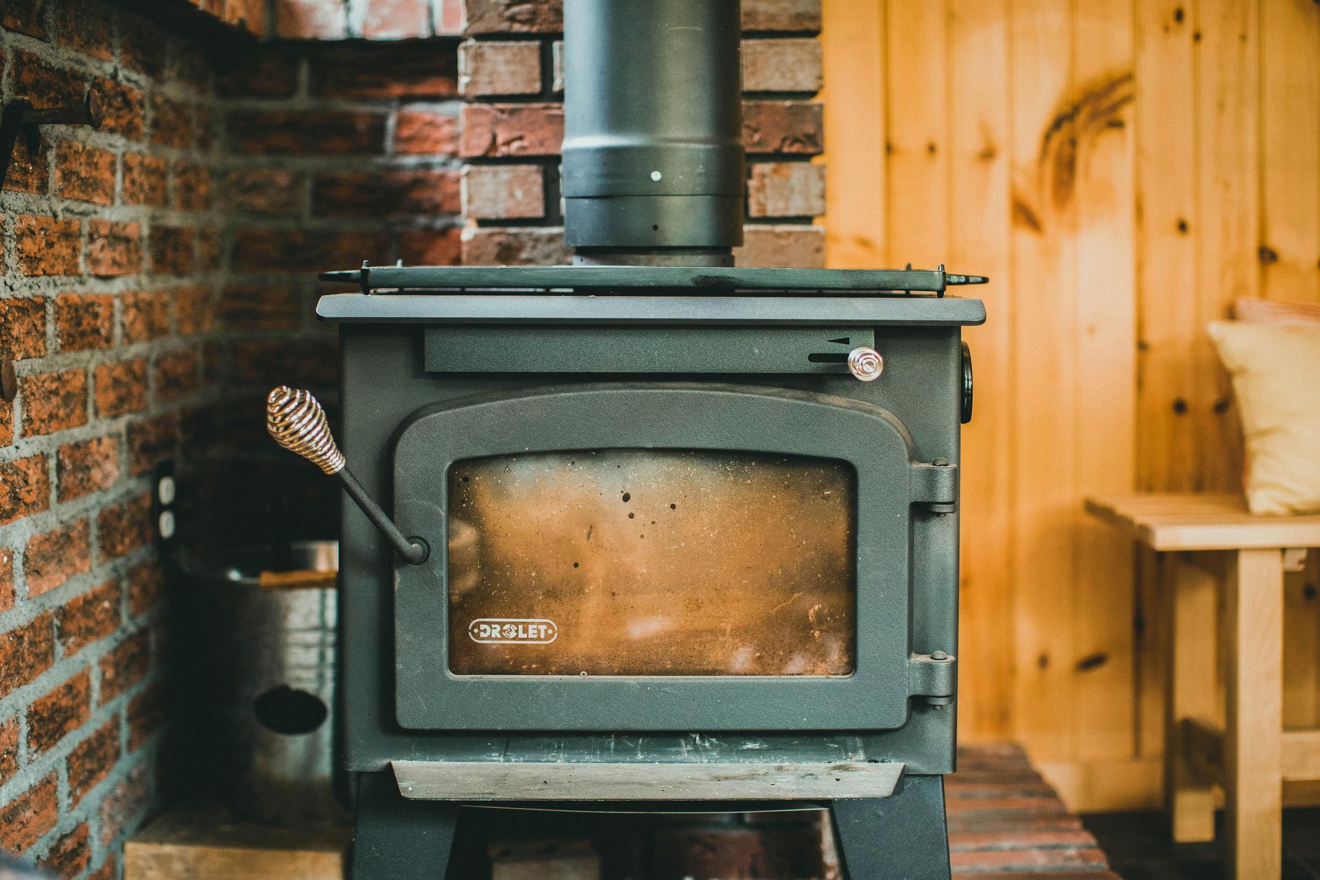 Green wood-burning stove in a cozy room with brick and wood-paneled walls