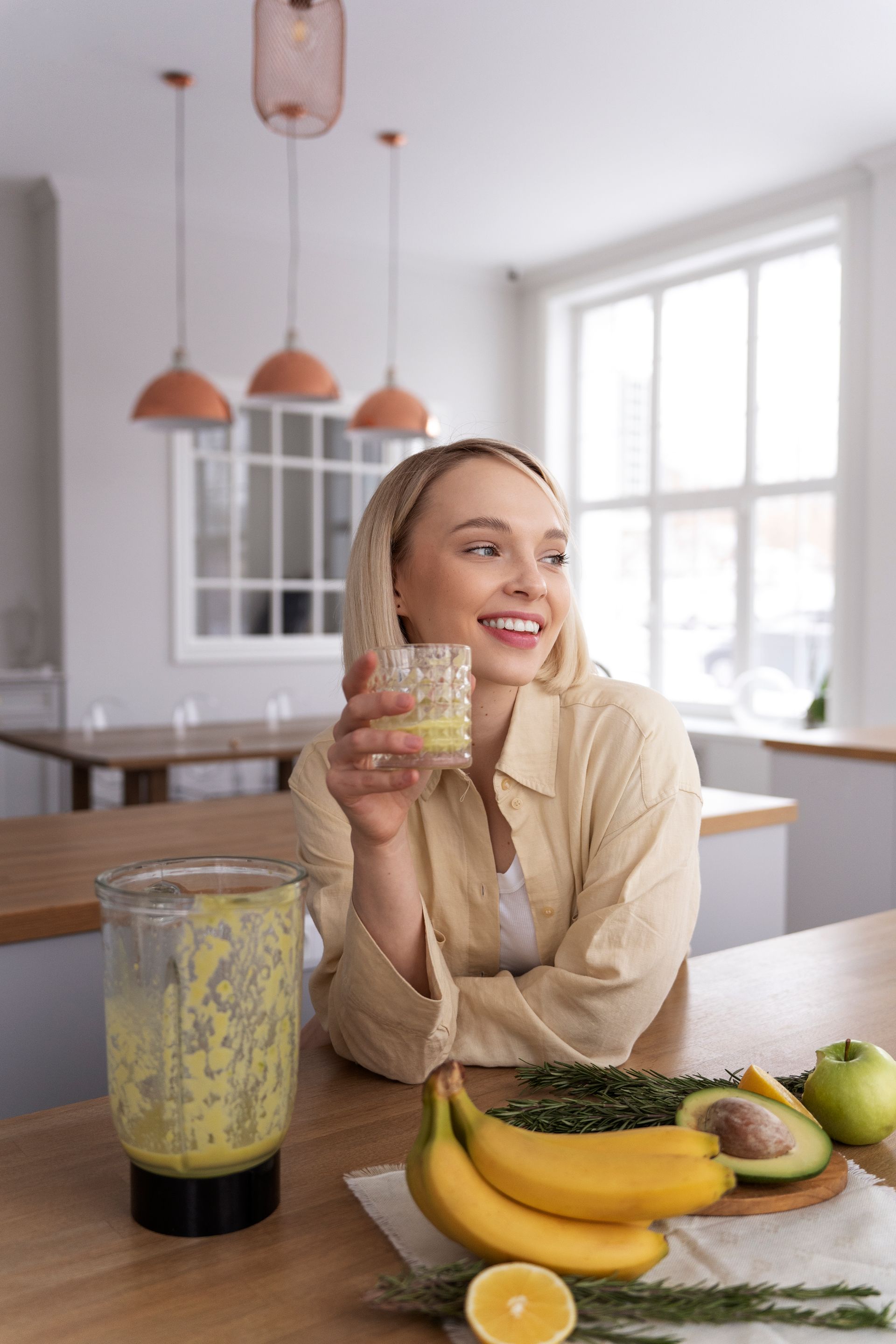 A woman is sitting at a table drinking a smoothie.