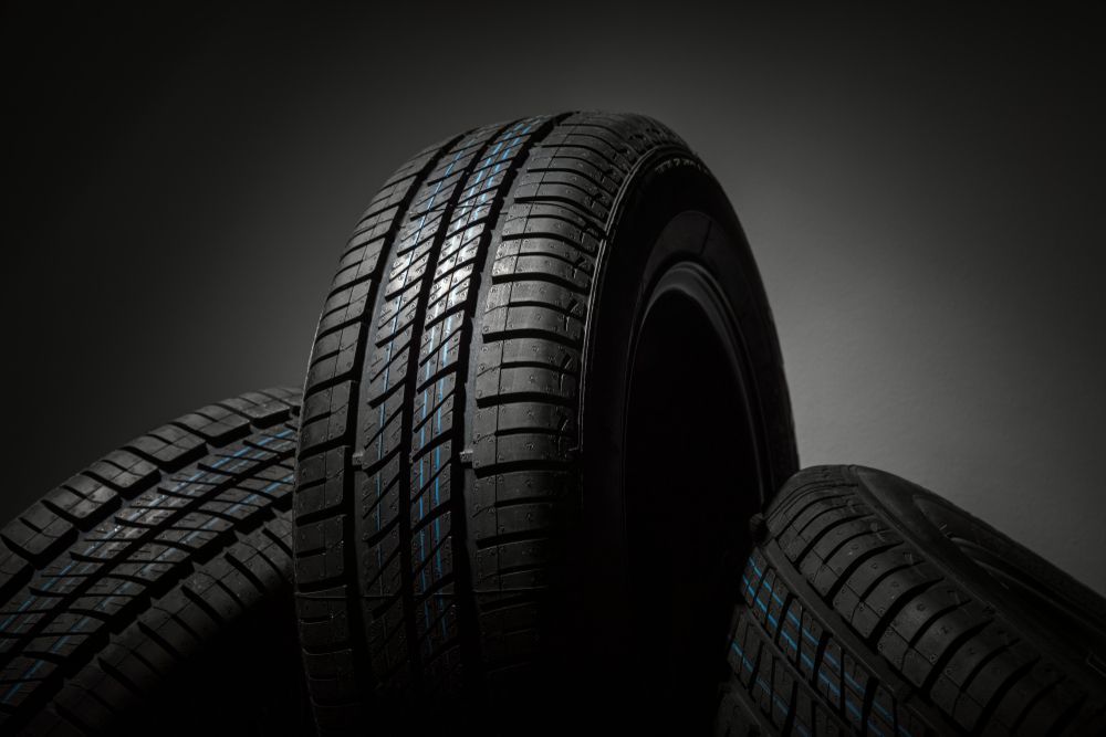 Three Black Car Tires Stacked Against a Gray Backdrop — Bob Kolln Automotive In Toukley, NSW