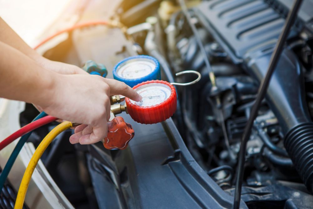 Hands Adjusting Gauges on Car Air Conditioning System in Engine Bay — Bob Kolln Automotive In Gorokan, NSW