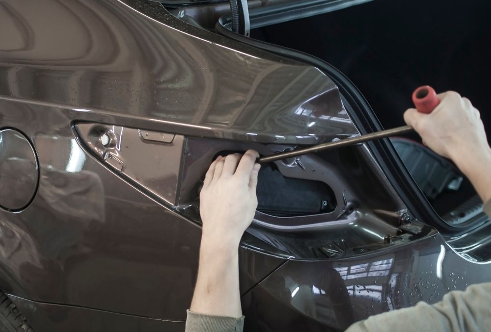 Person Using a Tool to Work on a Car's Trunk — Bob Kolln Automotive In Charmhaven, NSW