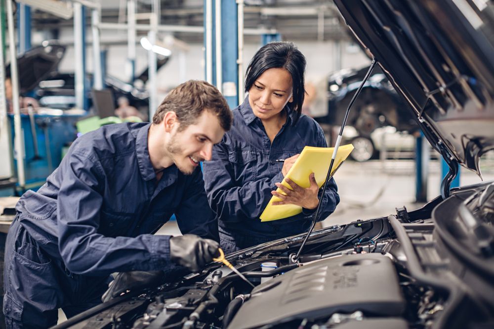 Mechanic Checks Oil While Another Holds Clipboard in an Auto Repair Shop — Bob Kolln Automotive In Charmhaven, NSW