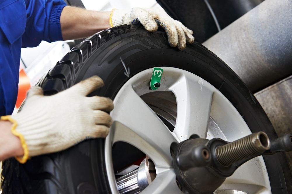 A Mechanic in Gloves Balancing a Tire on a Machine, Inside a Shop — Bob Kolln Automotive In Charmhaven, NSW