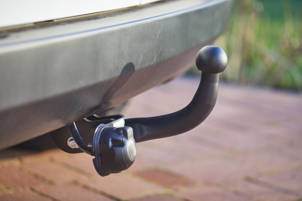 Black Tow Hitch Mounted on the Rear of a White Car, Resting on a Brick Patio — Bob Kolln Automotive In Toukley, NSW