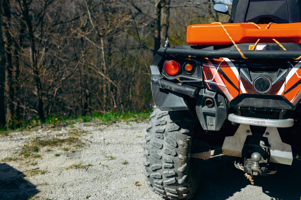 Rear View of an Orange and Black Atv Parked on a Gravel Road — Bob Kolln Automotive In Charmhaven, NSW