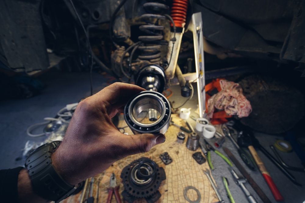 Person Holding a Bearing, Surrounded by Car Parts and Tools on a Workbench — Bob Kolln Automotive In Warnervale, NSW