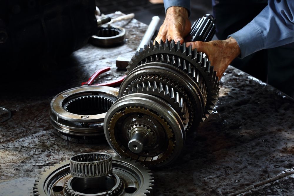 Mechanic Holding a Disassembled Transmission Gear Set — Bob Kolln Automotive In Charmhaven, NSW