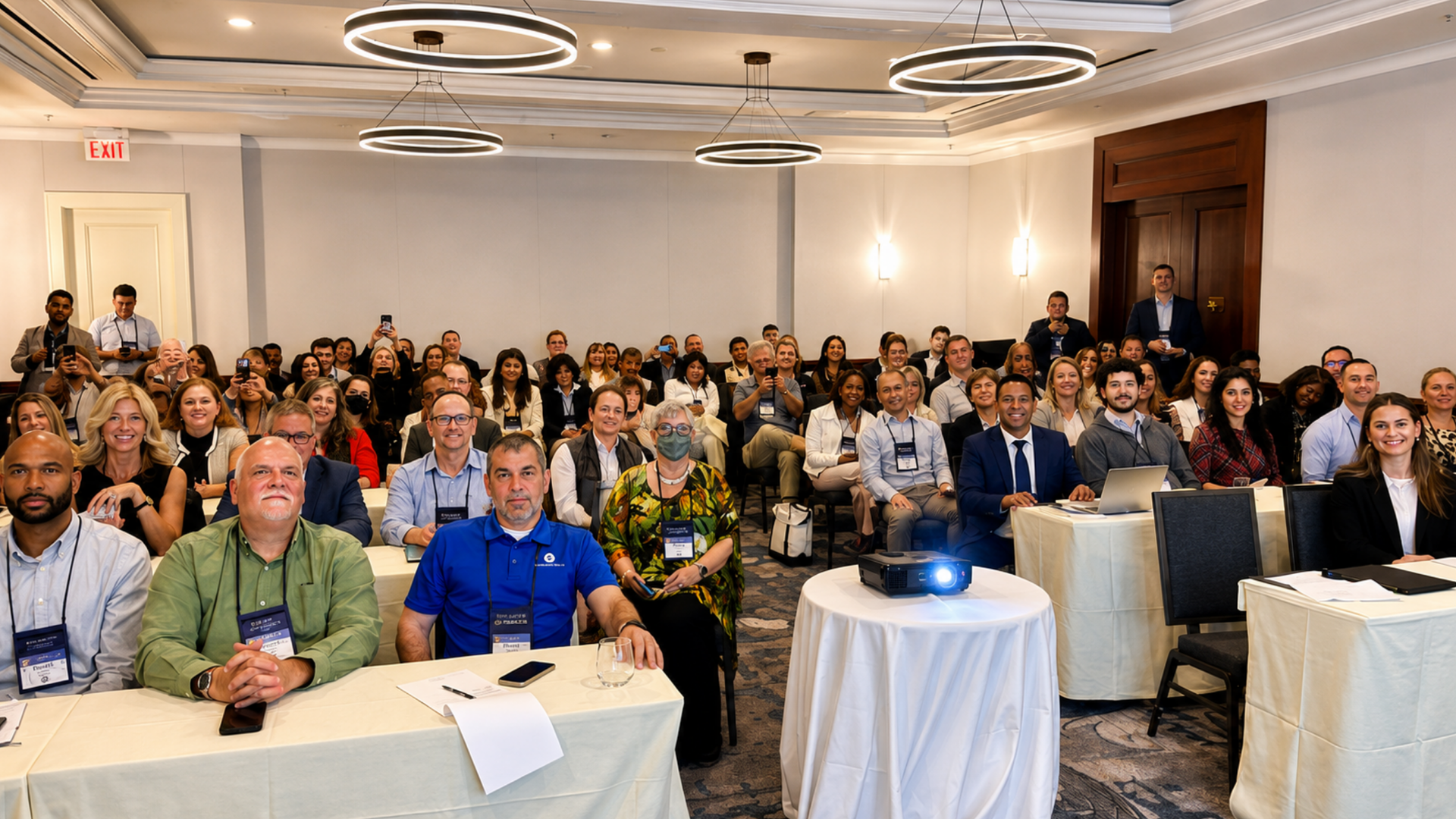 Audience seated at a conference table, facing a presentation in a hotel meeting room