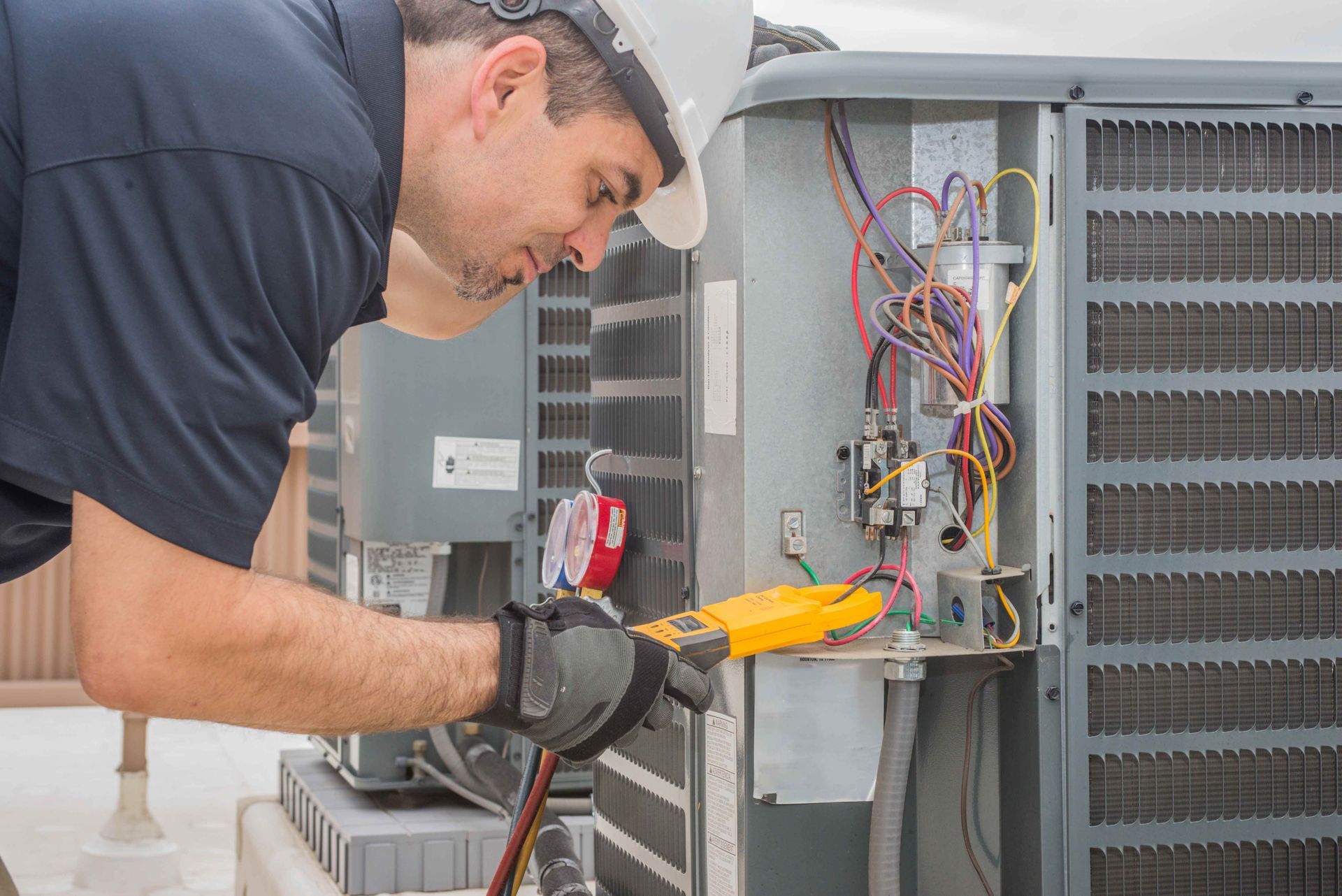 a man is working on an air conditioner with a multimeter