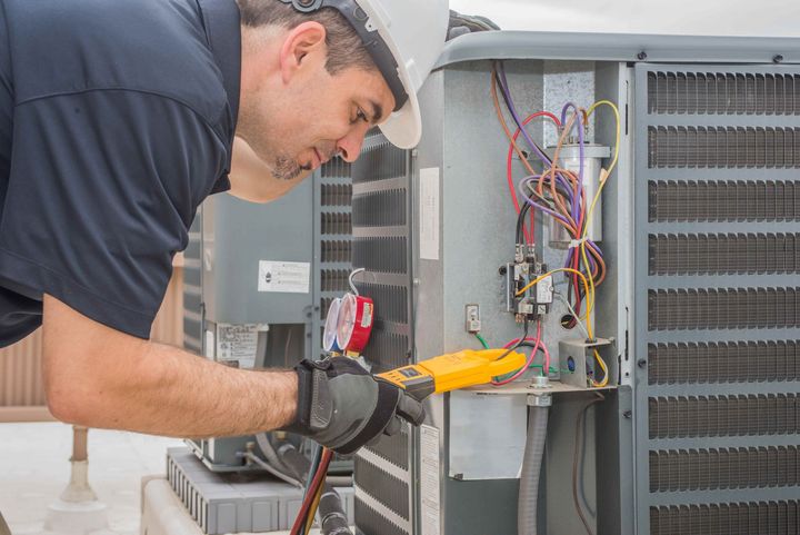 a man is working on an air conditioner with a pair of pliers 