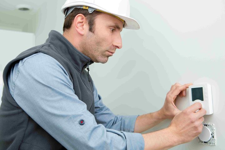 a man is adjusting a thermostat on a radiator in a living room .