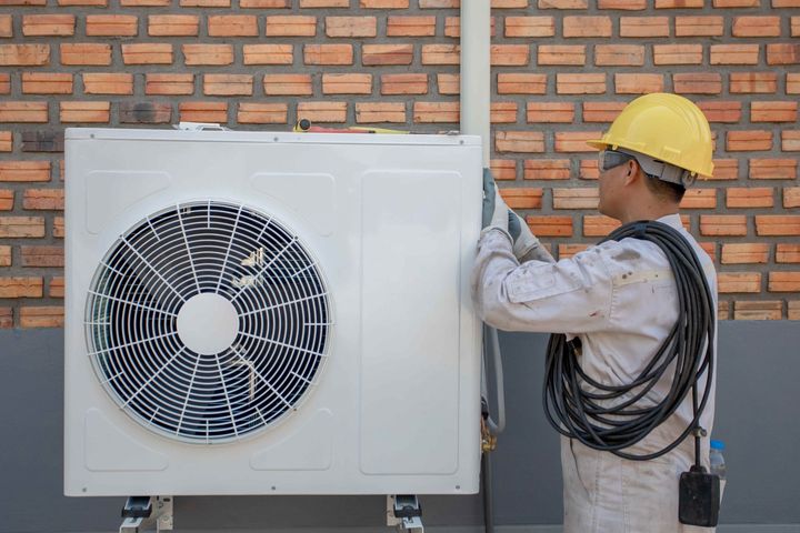 a man is installing an air conditioner on a brick wall