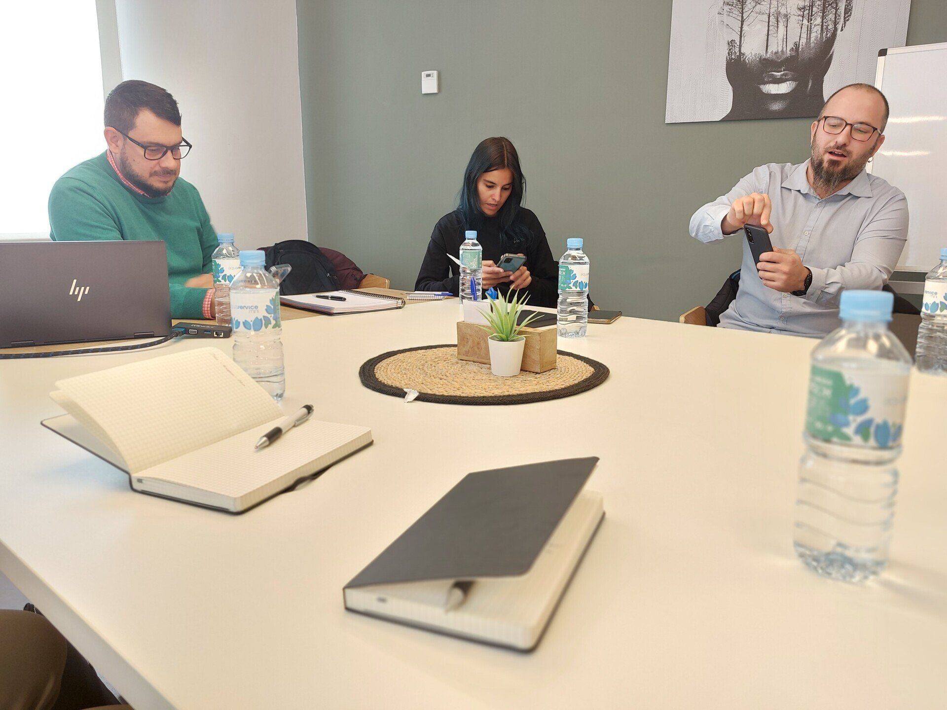 Un grupo de personas están sentadas alrededor de una mesa con cuadernos y botellas de agua.