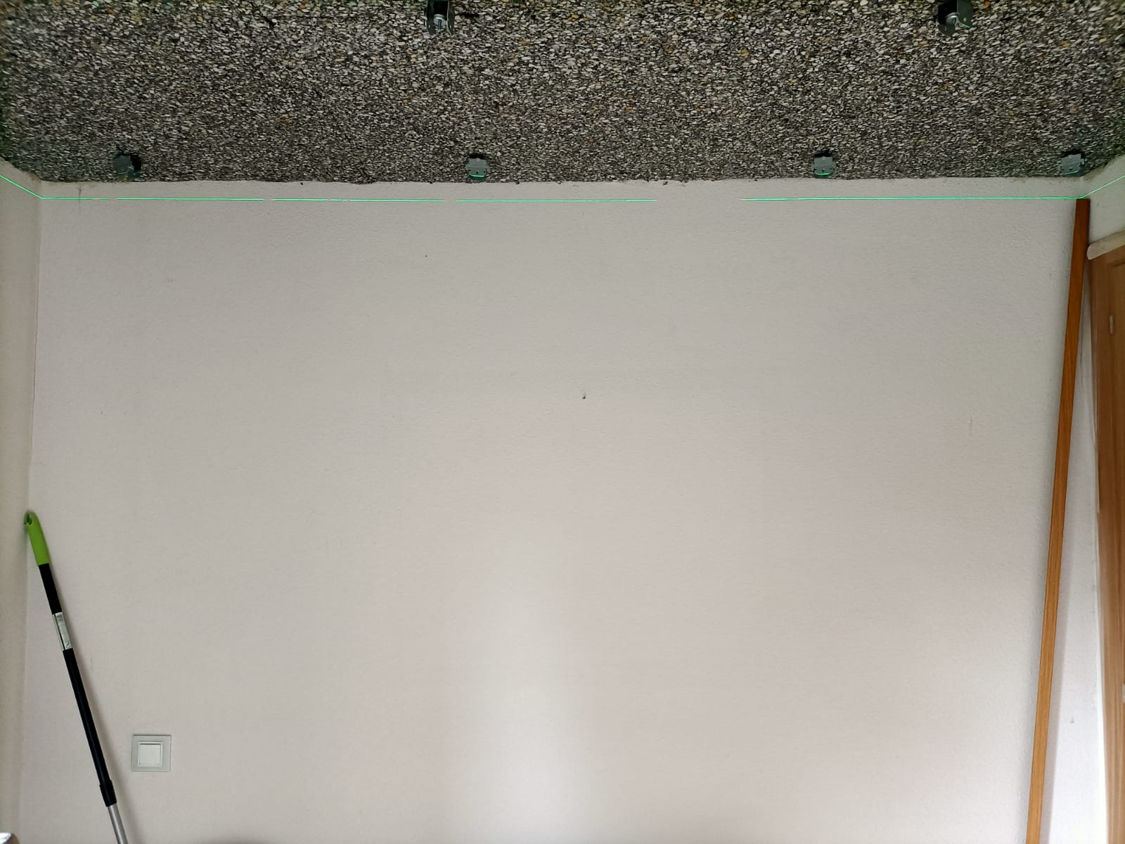 Una habitación con una pared blanca y una escoba en el suelo.