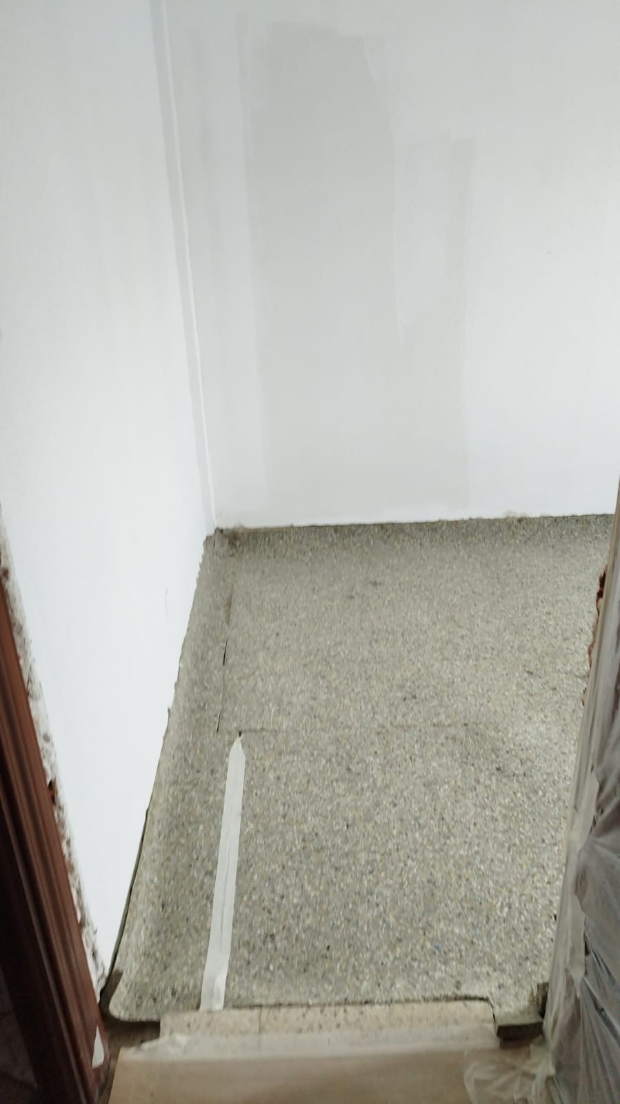 Una habitación con piso alfombrado y una pared blanca.