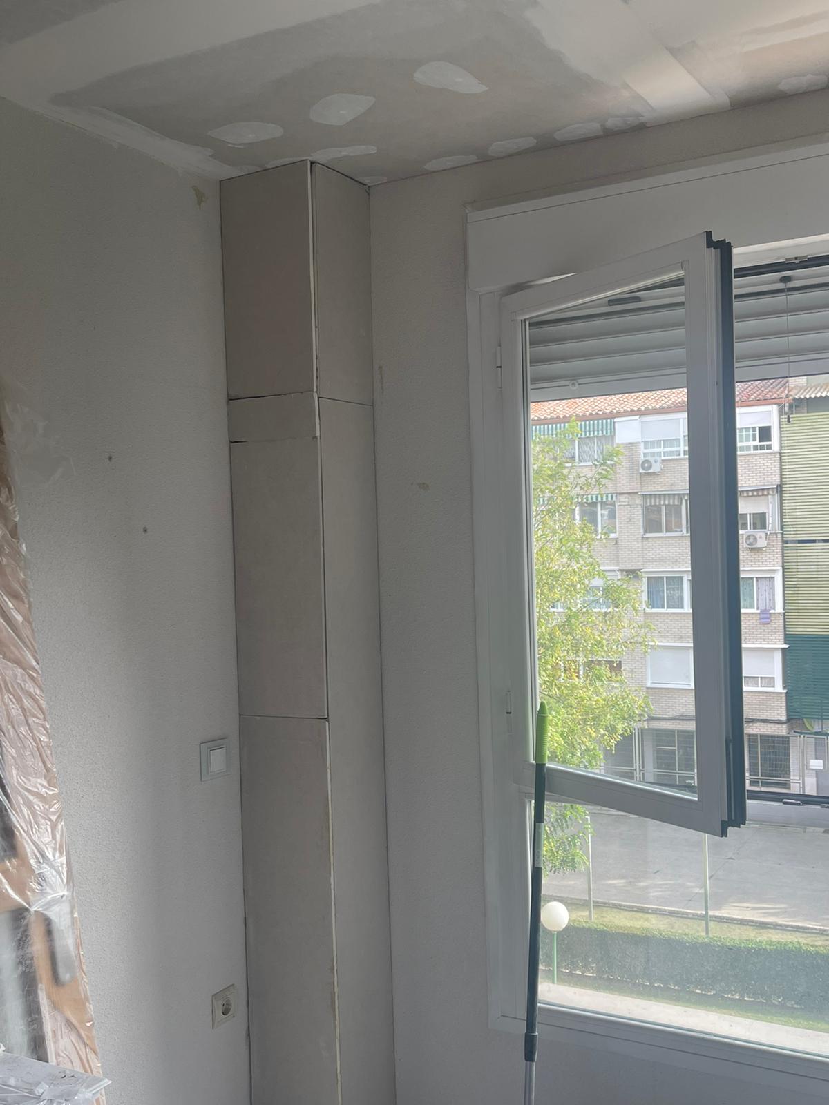Una habitación con una ventana y un edificio al fondo.