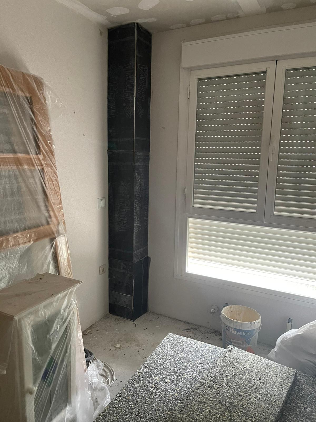 Una habitación con chimenea y ventana con contraventanas.