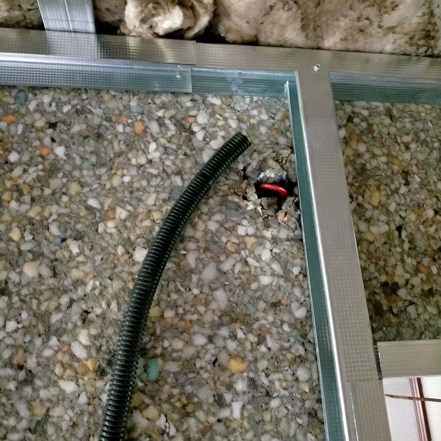 Una manguera negra está colocada sobre una superficie rocosa junto a un marco de metal.