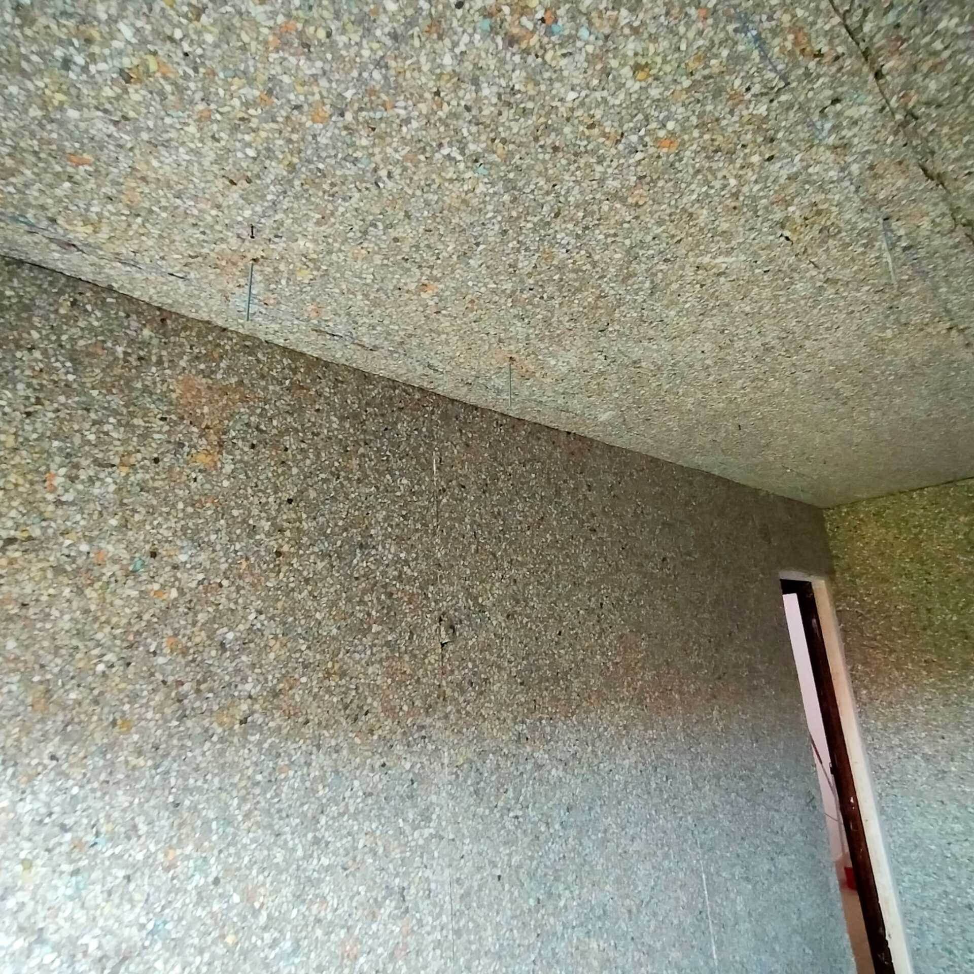 Una habitación con un techo de madera contrachapada y una puerta.