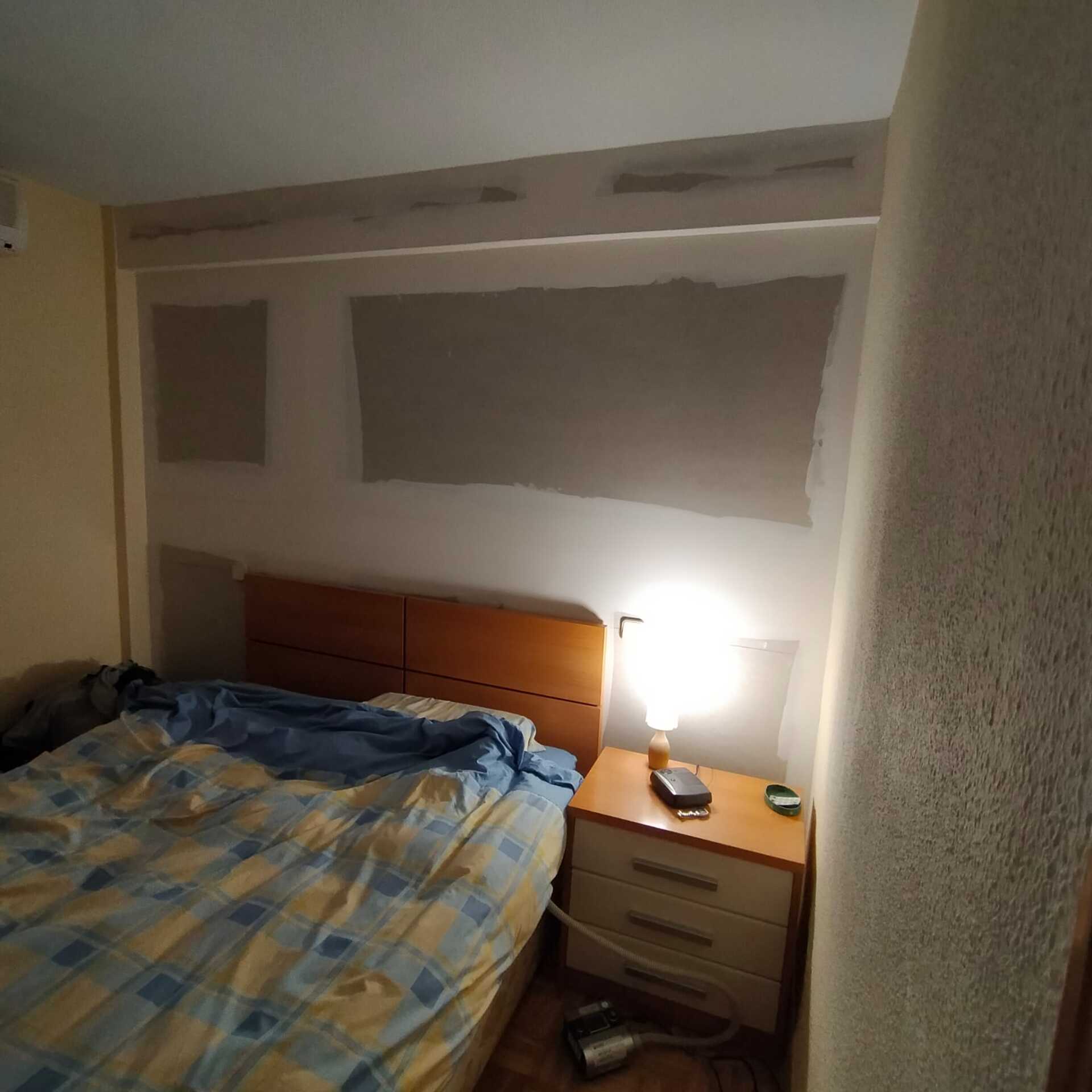 Un dormitorio con una cama, una mesita de noche y una lámpara
