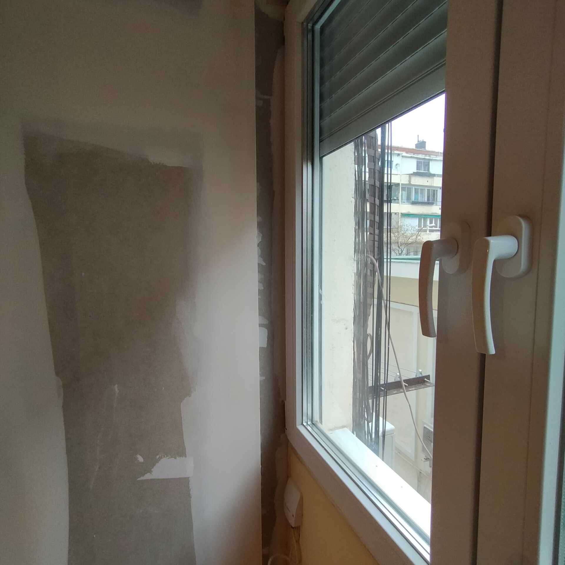 Una ventana con una persiana y un tirador blanco