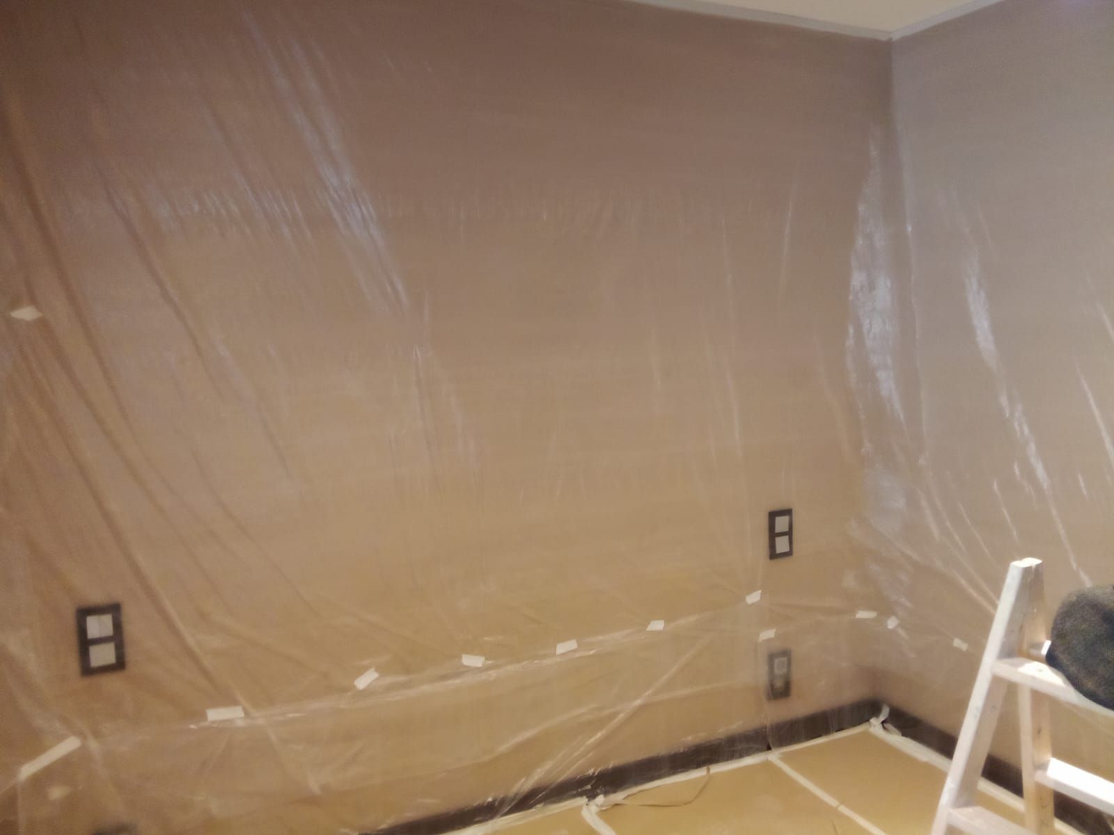 Una habitación con una escalera y una pared cubierta de plástico
