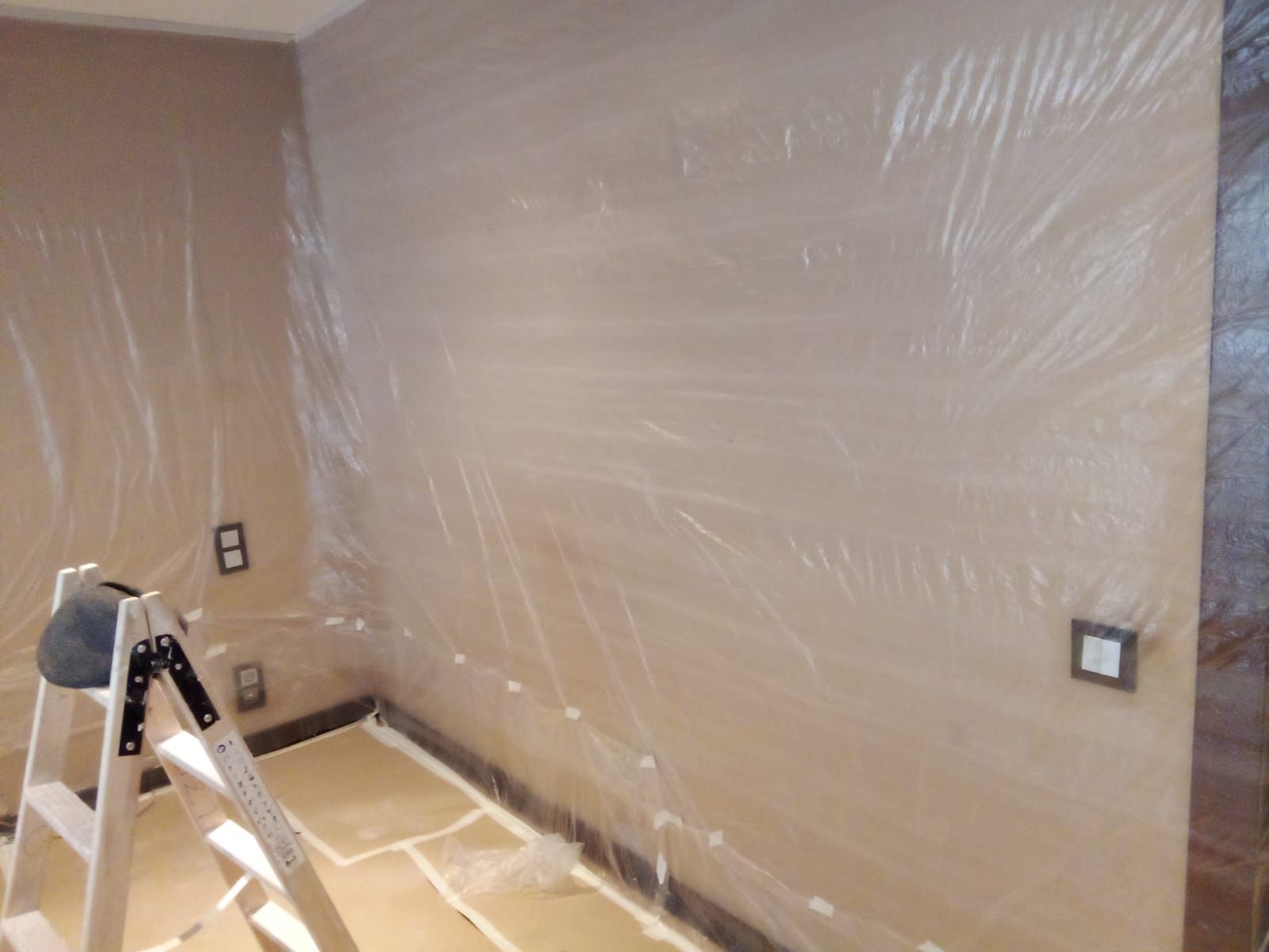 Una habitación con una escalera y una pared cubierta de plástico