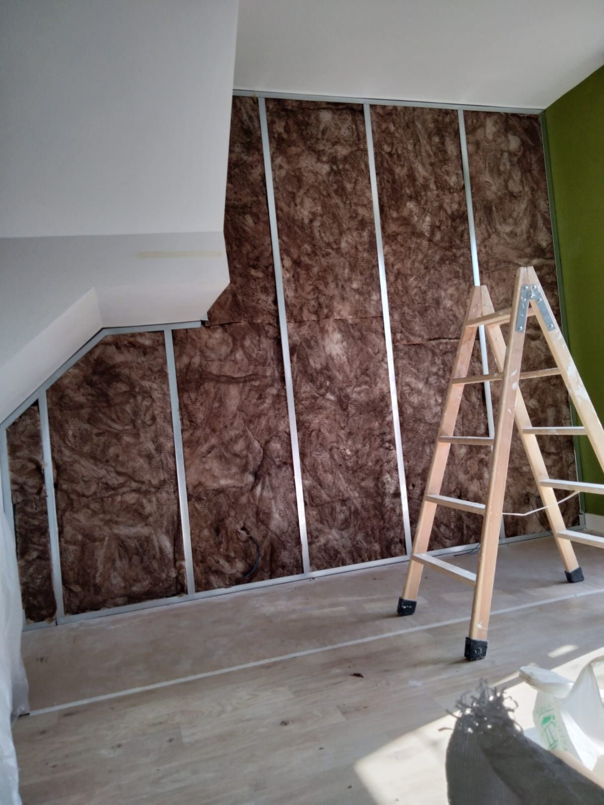 Una escalera de madera está colocada frente a una pared con aislamiento.