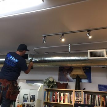 A man wearing a shirt that says fire is working on a ceiling