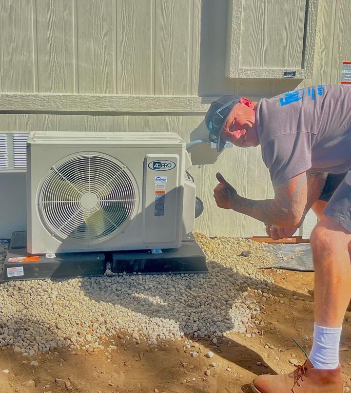 A man is working on an air conditioner outside of a building.