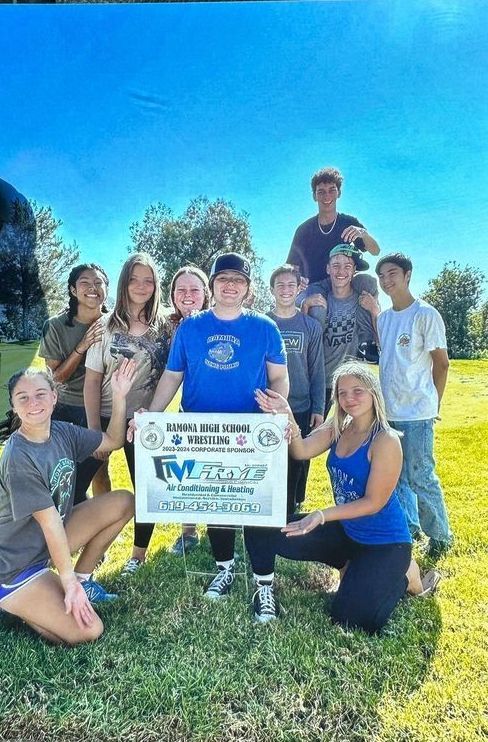 A group of people standing in a field holding a sign.