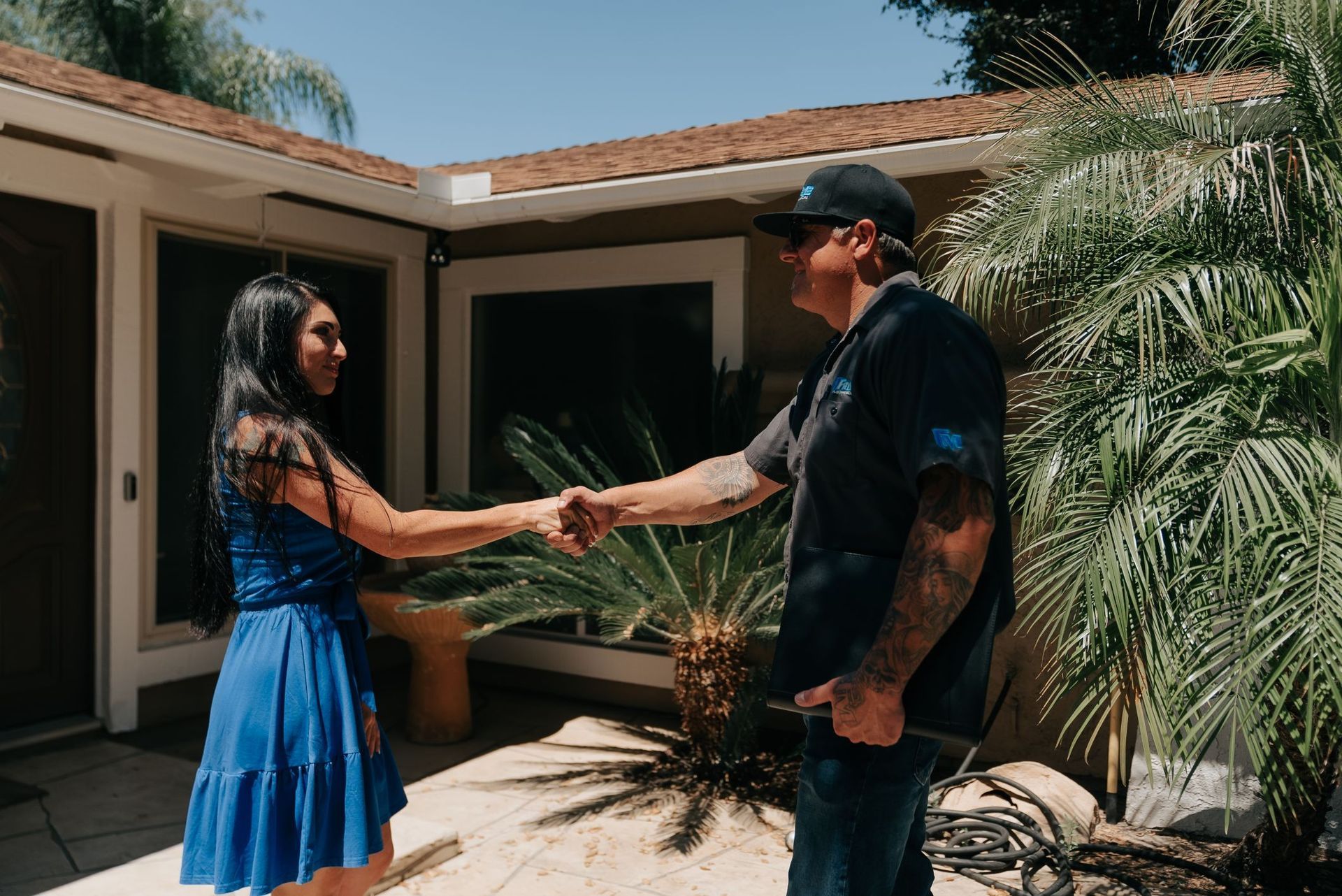 A man and a woman are shaking hands in front of a house.