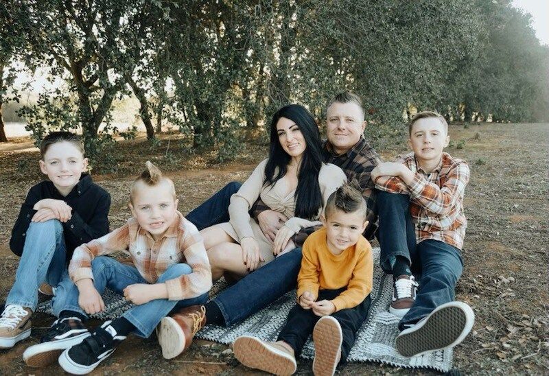 A family is sitting on a blanket in a field.