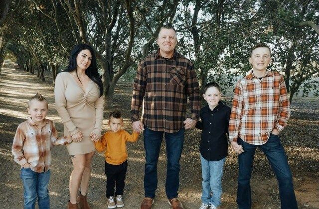 A family is posing for a picture in a park while holding hands.