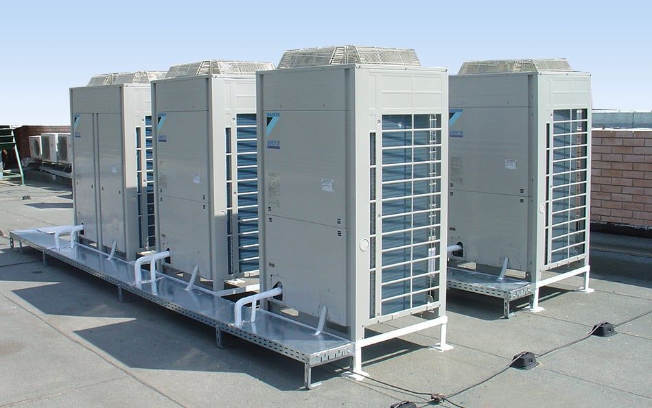 A row of air conditioners are sitting on top of a roof.