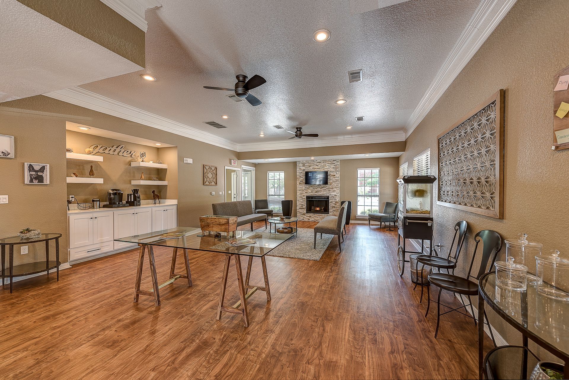 A large room with hardwood floors , tables , chairs and a ceiling fan.