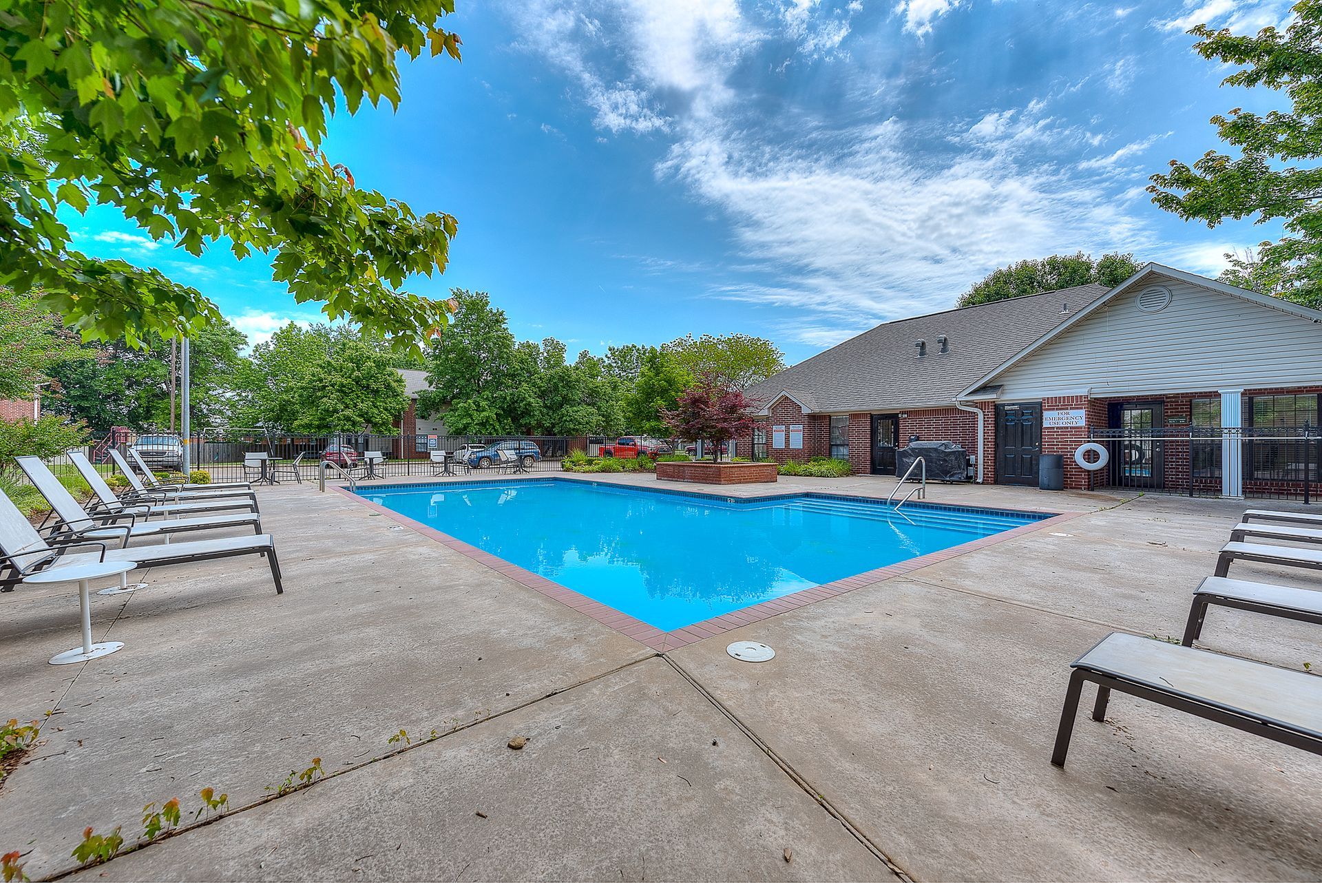 A large swimming pool is surrounded by lawn chairs and a building.
