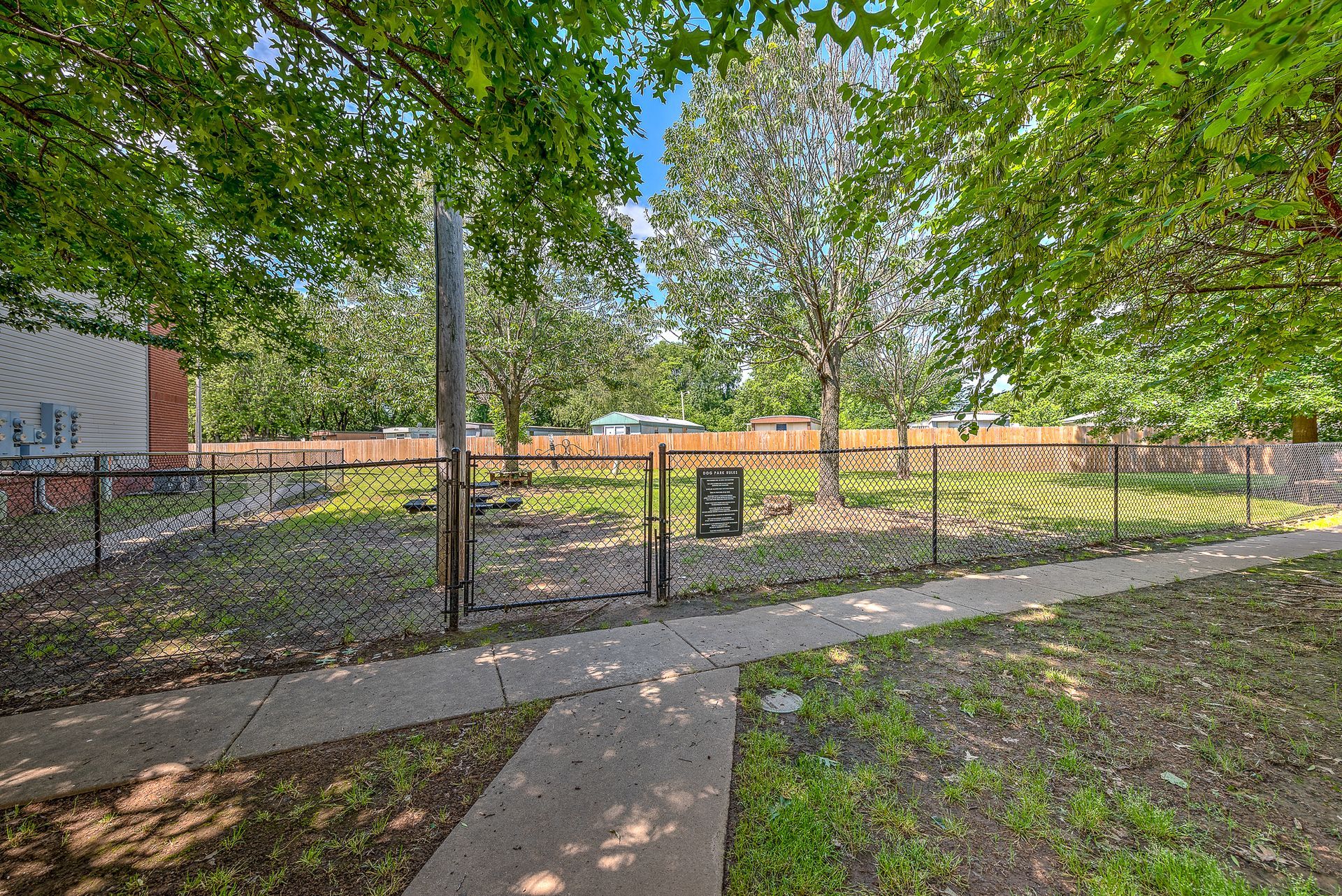 A fenced in area with a sidewalk and trees in the background.